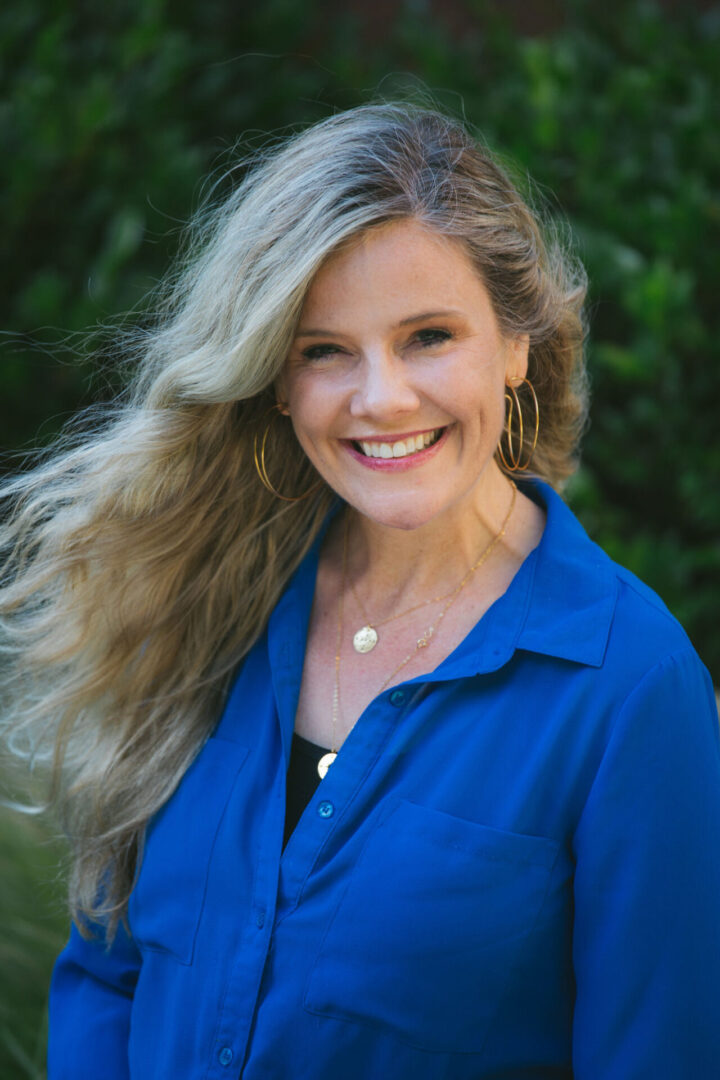 A woman with long blonde hair wearing blue shirt.