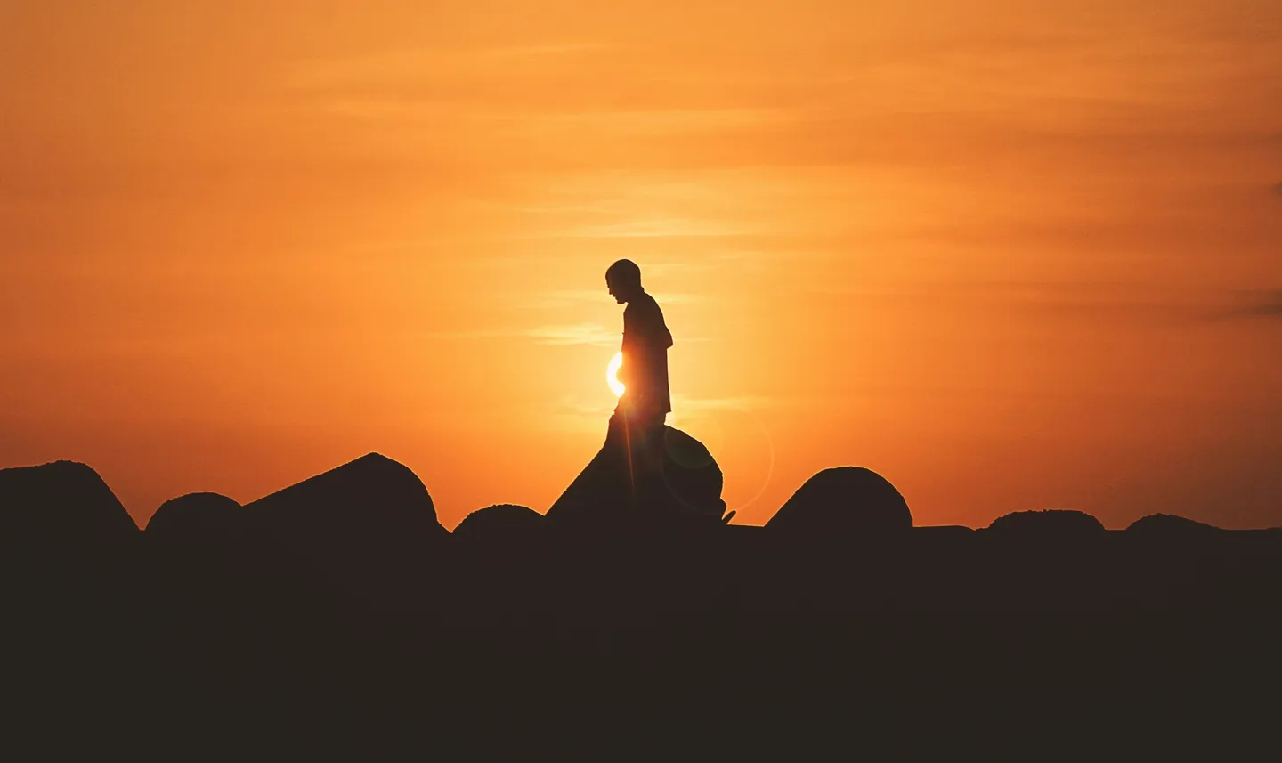 A person standing on top of rocks at sunset.